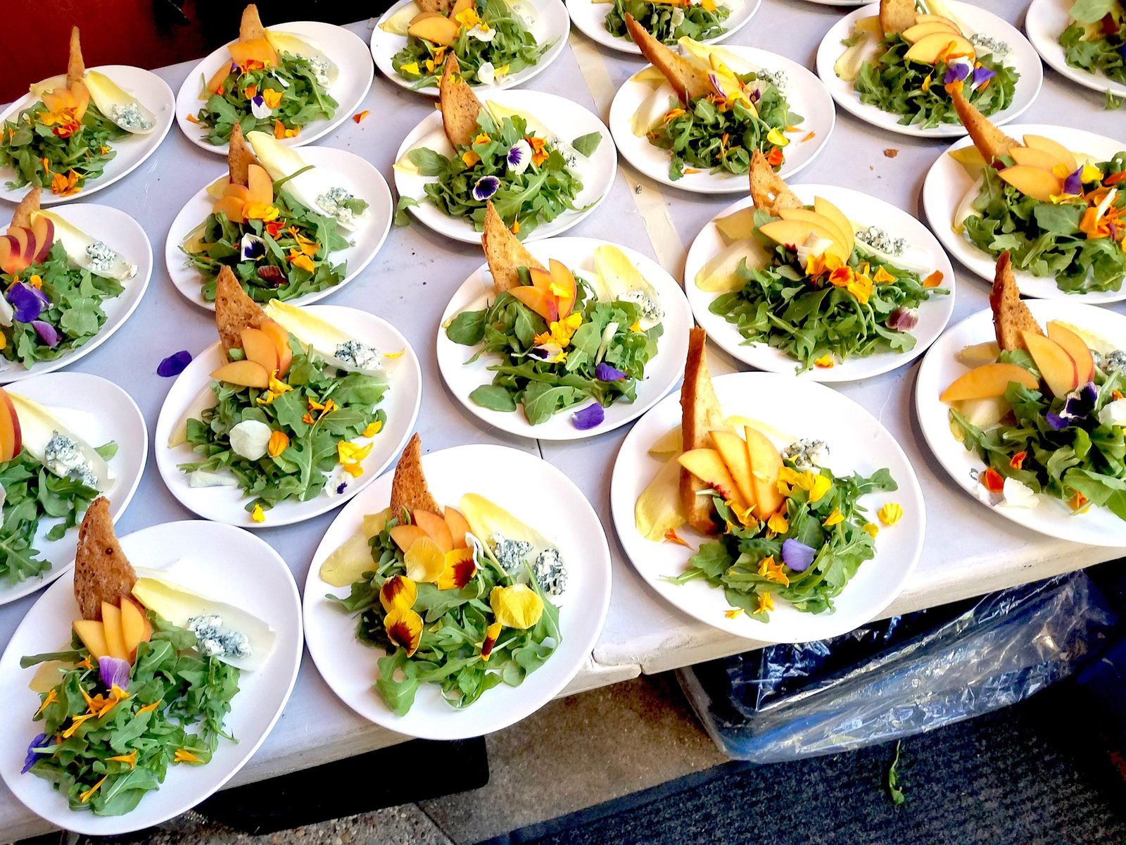 Endive and Arugula salad  with seasonal fruit, gorgonzola and agave chipotle vinaigrette - Garnished with edible flowers